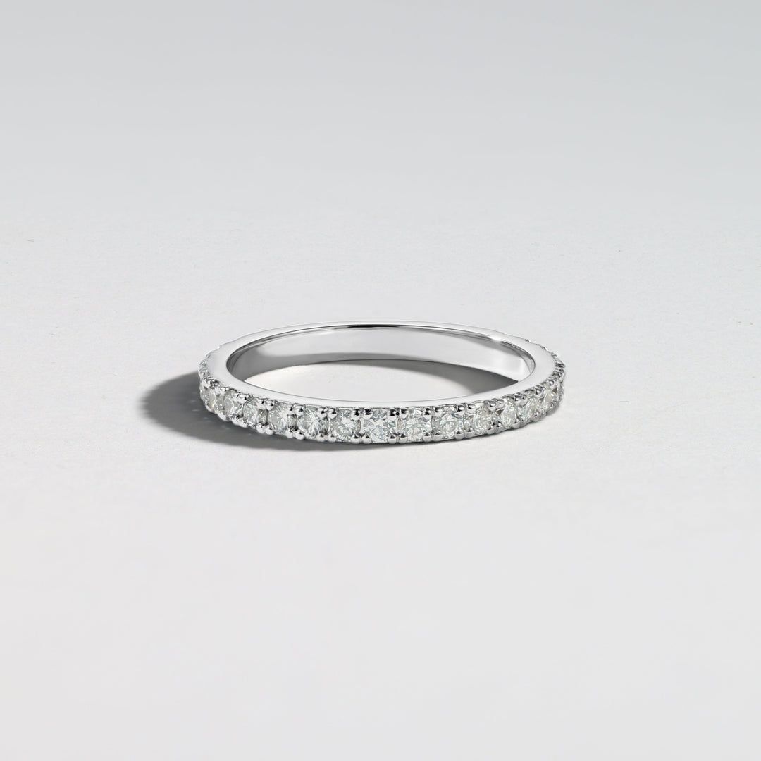 A thin silver band ring paved with small clear stones, photographed on a clean light gray background #material_white