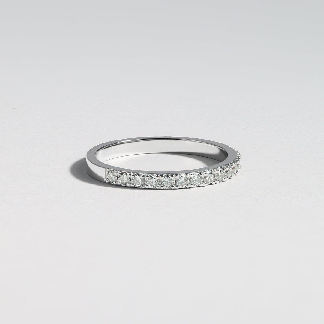 A thin silver band ring with a row of small clear pavé stones along the front, photographed on a clean light gray background #material_white