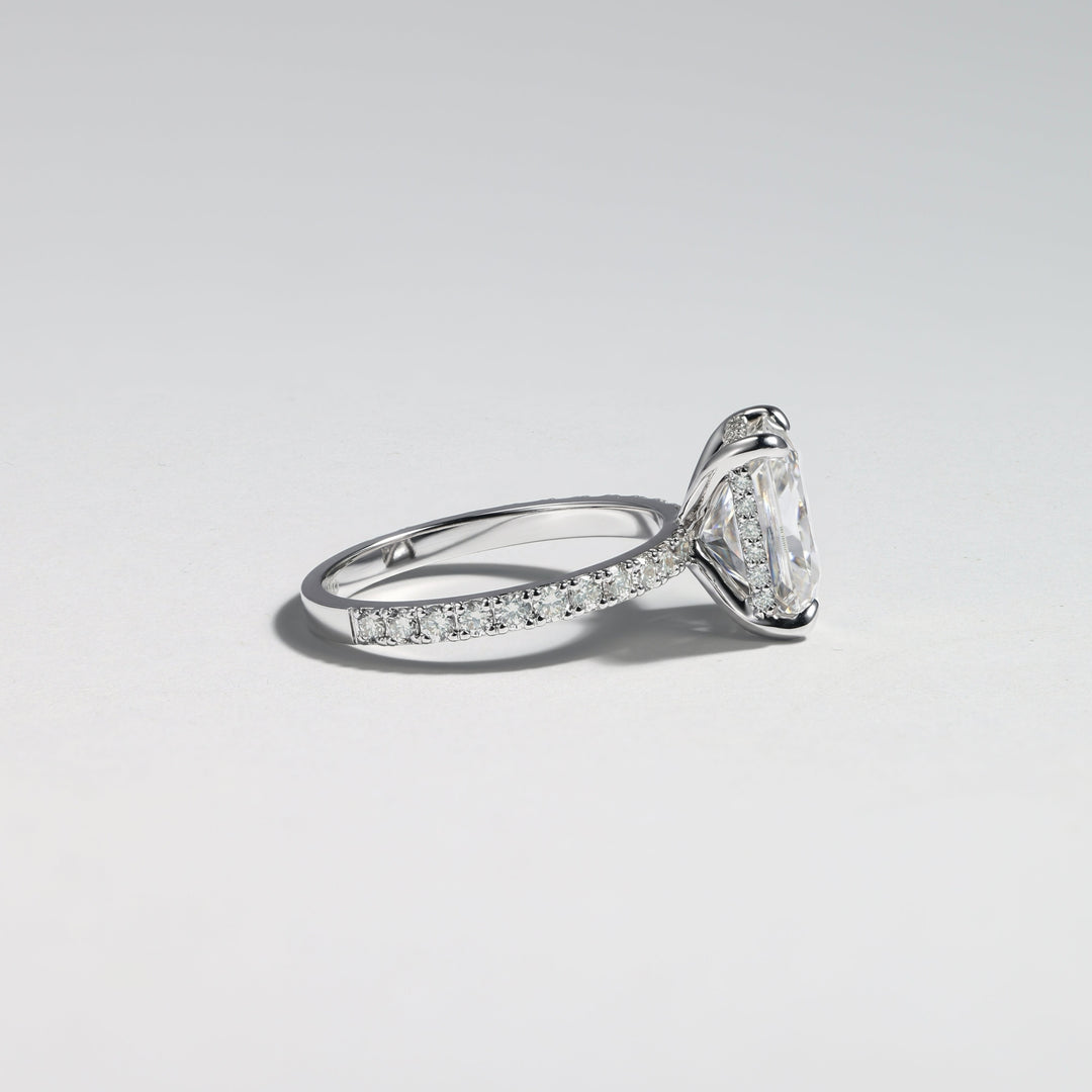 A silver-tone diamond ring with a large pear-cut center stone and pavé-set diamonds along the band, photographed on a clean light gray background #material_white