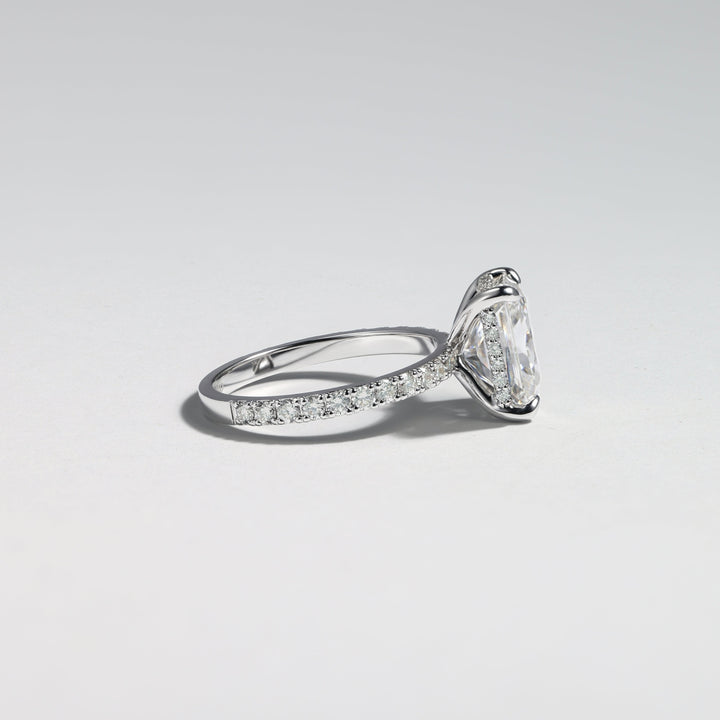 A silver-tone diamond ring with a large pear-cut center stone and pavé-set diamonds along the band, photographed on a clean light gray background #material_white