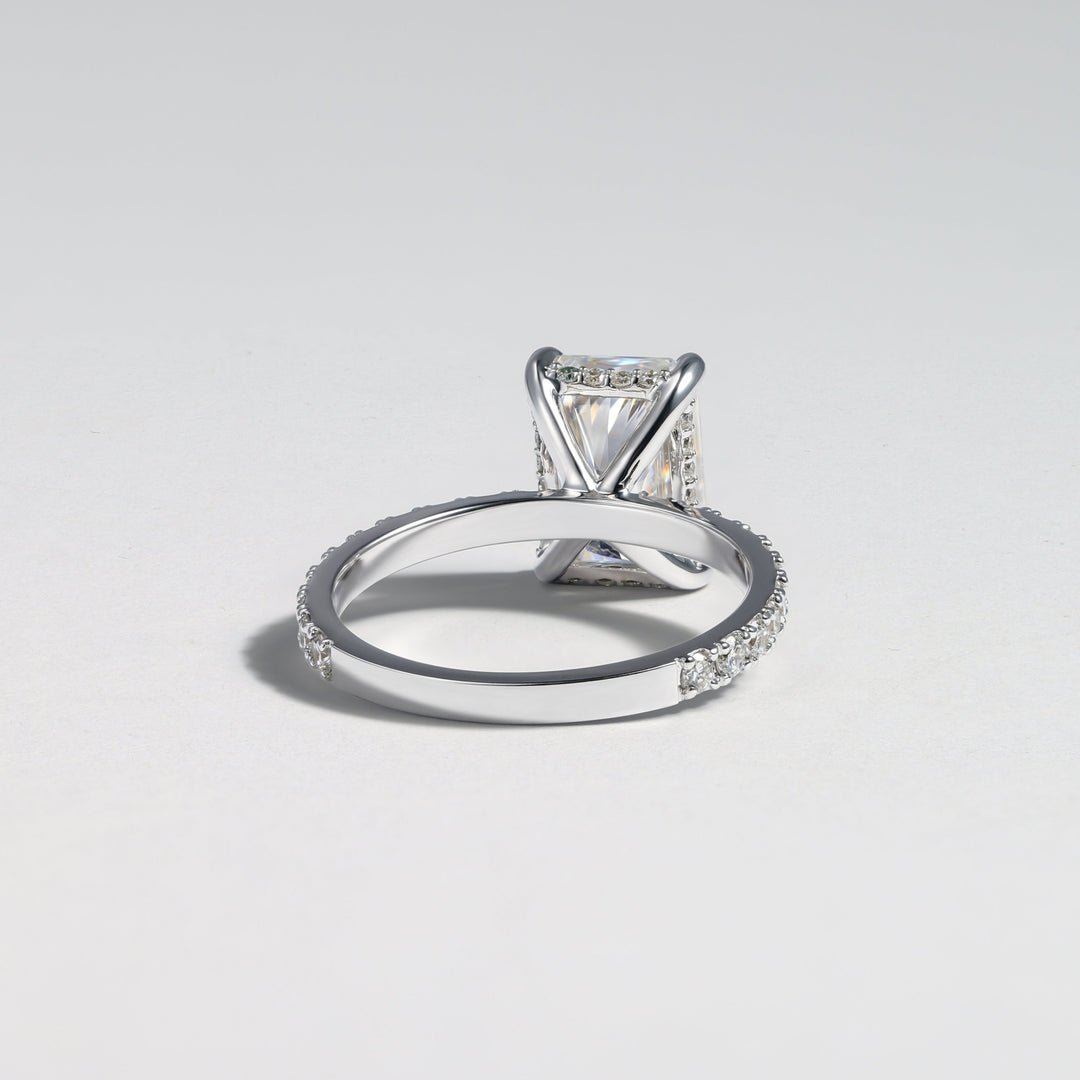 A silver-toned diamond ring with a square-cut center stone and pavé-set accent stones along the band, photographed on a clean light gray background #material_white