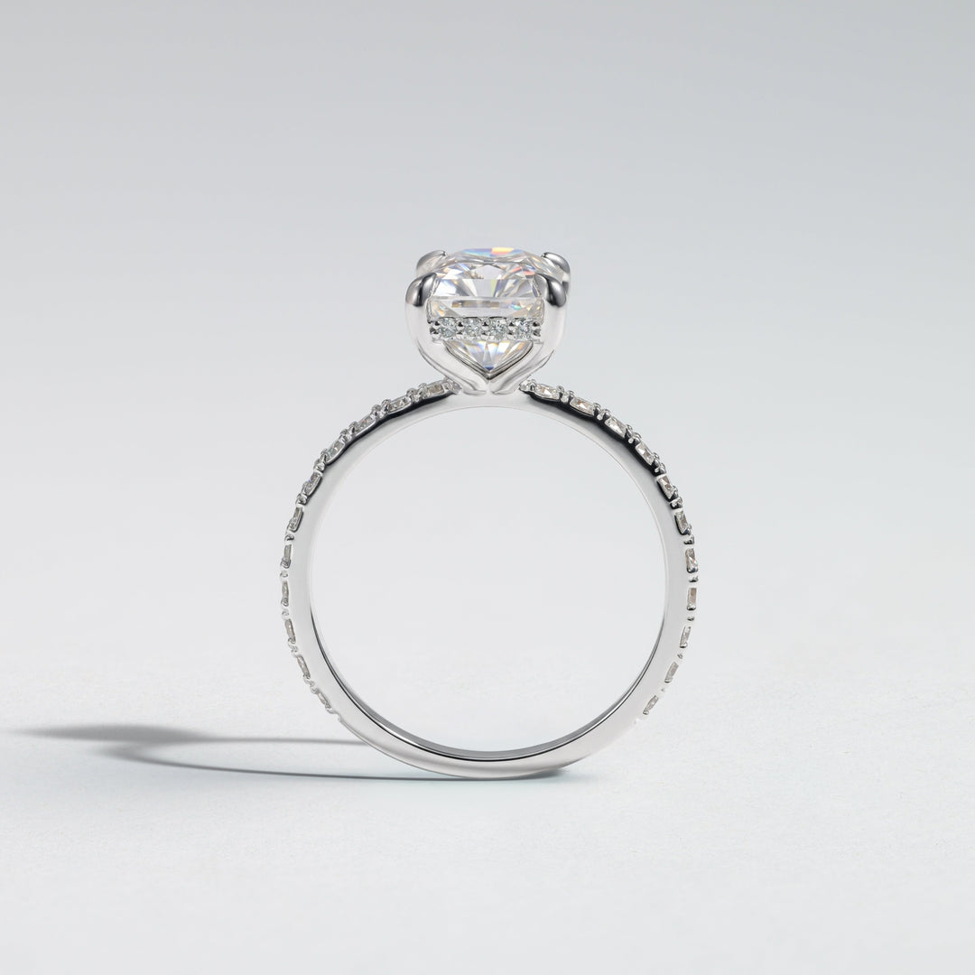 A silver-toned heart-shaped diamond engagement ring with a pavé band, photographed on a clean light gray background #material_white