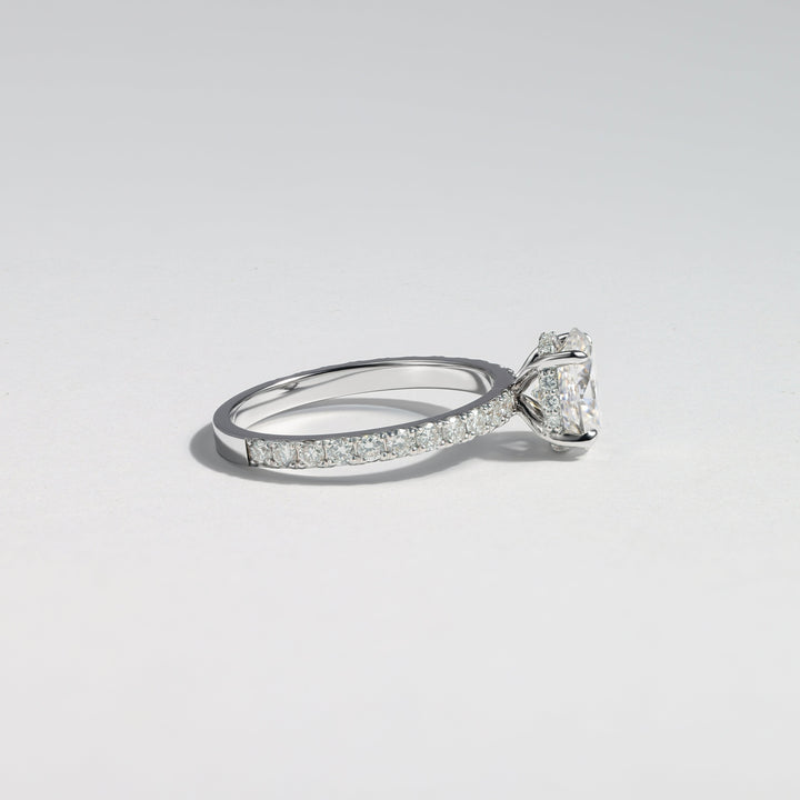 A silver-toned diamond engagement ring with a round-cut center stone and a pavé band, photographed on a clean light gray background #material_white