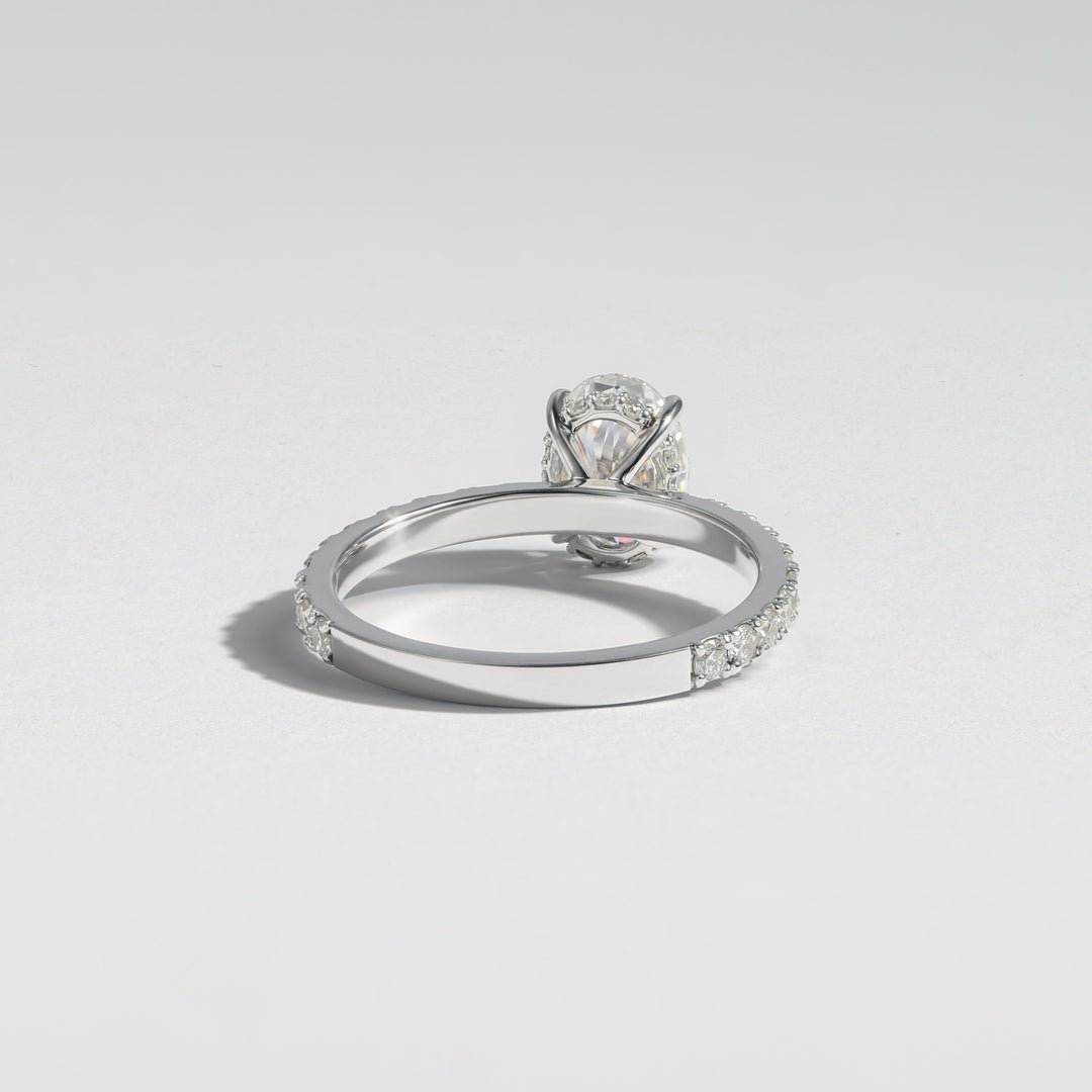 A silver-toned diamond ring with a round-cut center stone and a pavé band, photographed on a clean light gray background #material_white