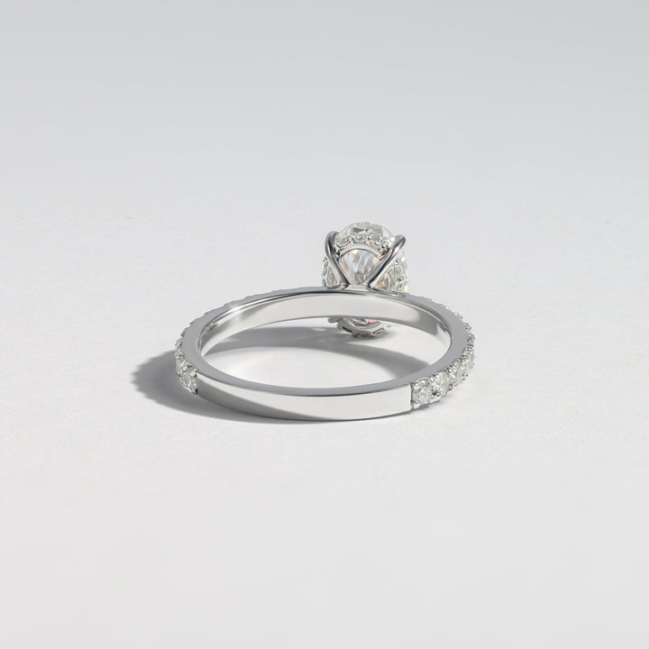 A silver-toned diamond ring with a round-cut center stone and a pavé band, photographed on a clean light gray background #material_white