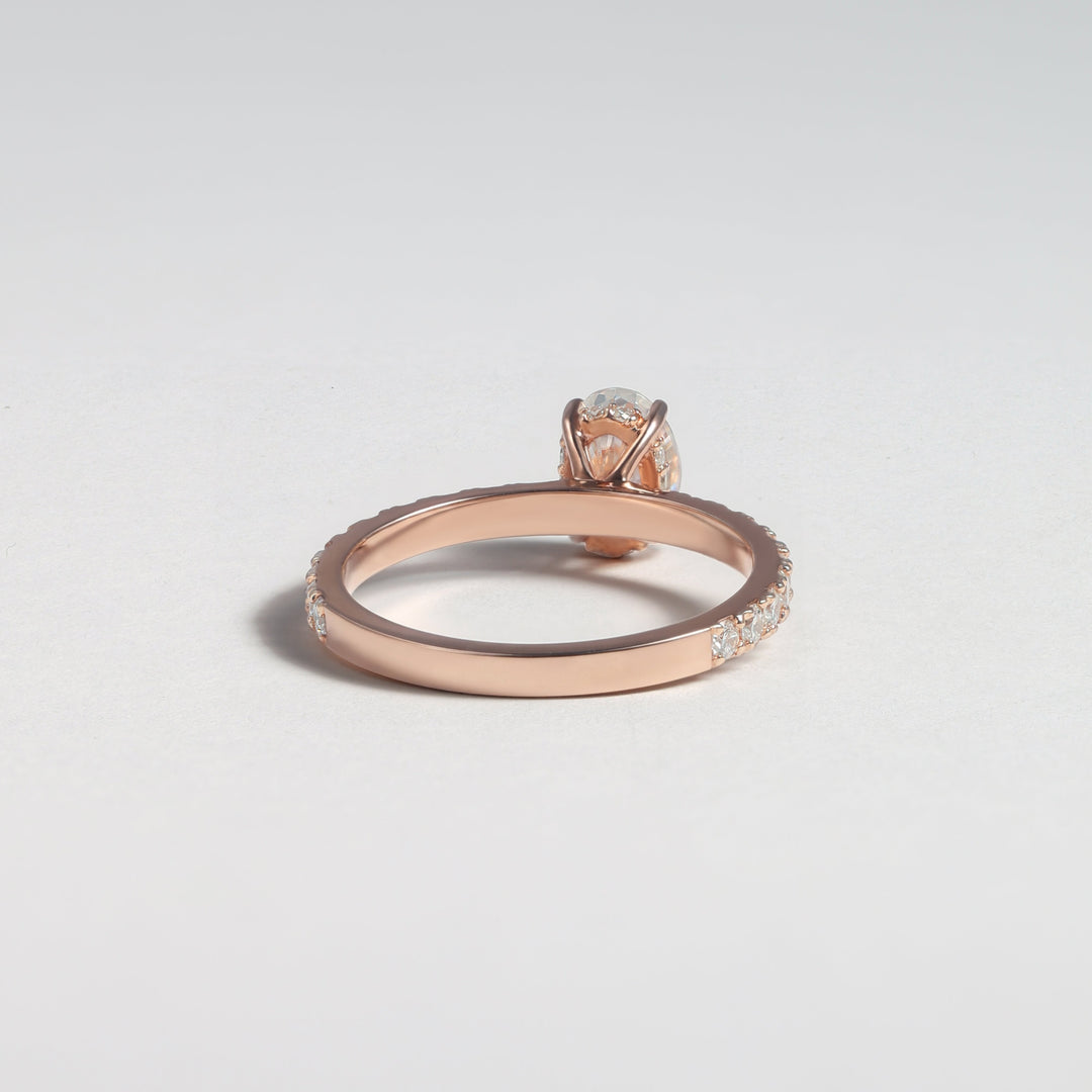 A rose gold ring with a small clear gemstone in a halo setting, shown on a light gray background #material_rose