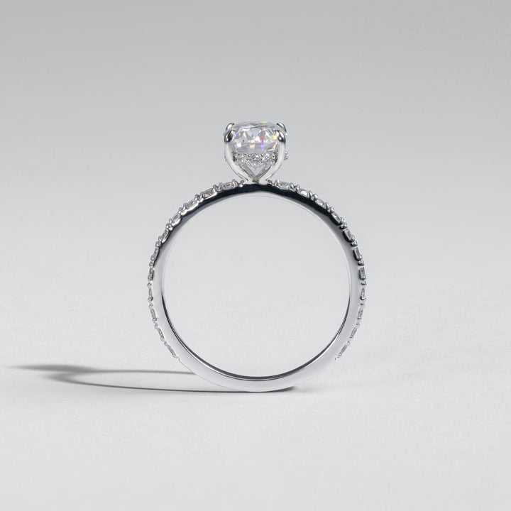 A silver-toned ring featuring a heart-shaped clear gemstone in a prong setting, with a pavé band, photographed on a neutral light gray background #material_white