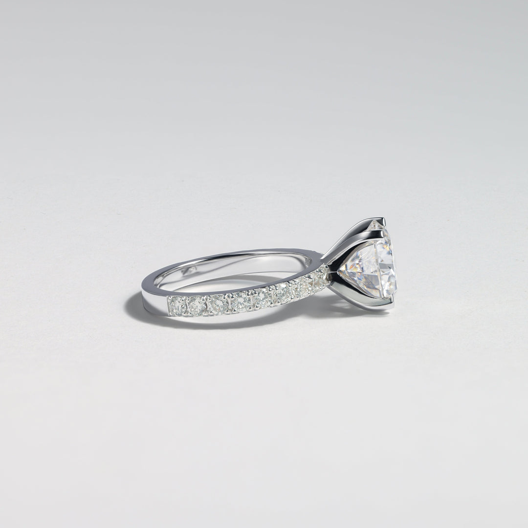 A silver-toned diamond ring with a triangular cluster of clear stones and a pavé band, photographed on a clean light gray background #material_white