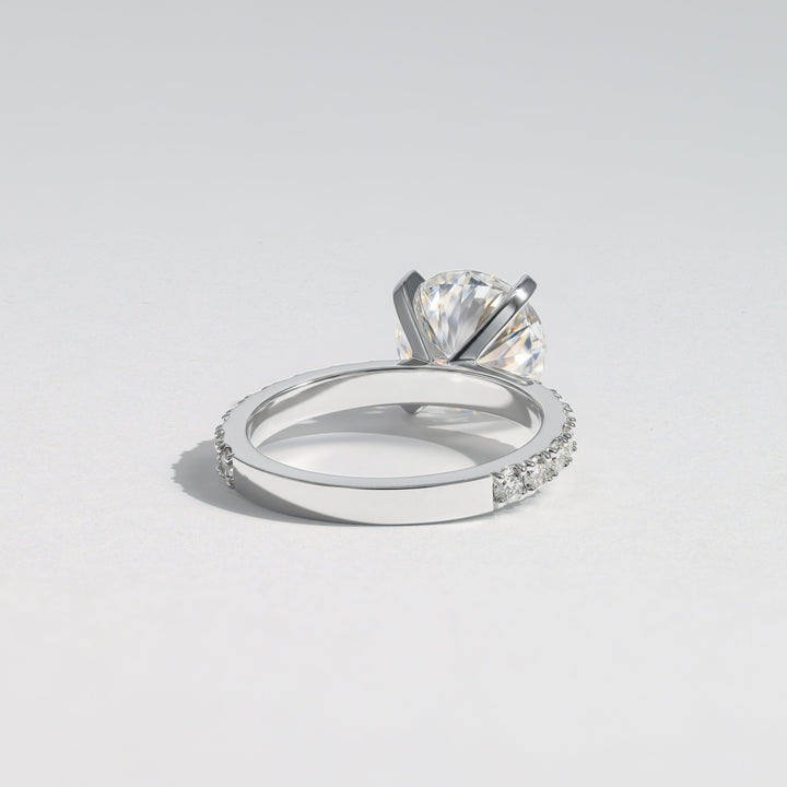 A silver-toned diamond ring with a large round-cut center stone and small pavé-set diamonds along the band, photographed on a clean light gray background #material_white