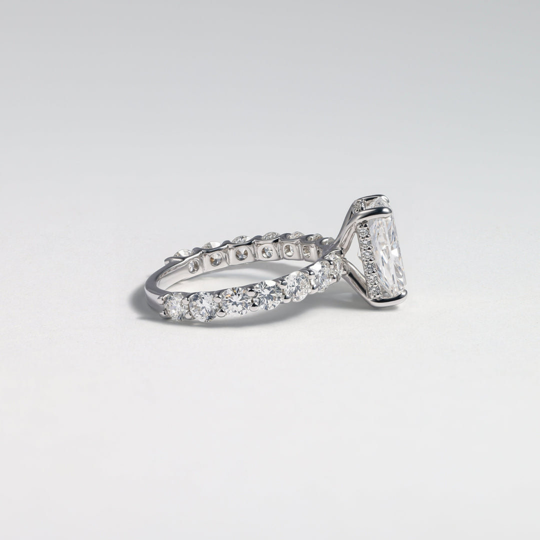 A silver-toned diamond ring featuring a large rectangular emerald-cut center stone and a pavé band, photographed on a clean light gray background #material_white