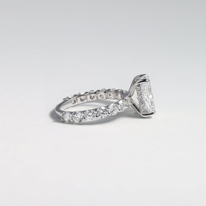 A silver-toned diamond ring featuring a large rectangular emerald-cut center stone and a pavé band, photographed on a clean light gray background #material_white