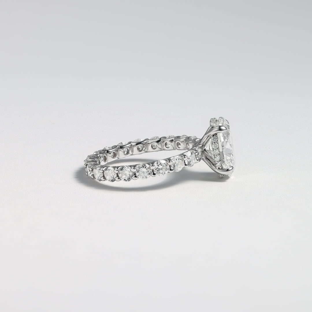 A silver-toned diamond ring with a triangular-cut center stone and a pavé band, photographed on a clean light gray background #material_white