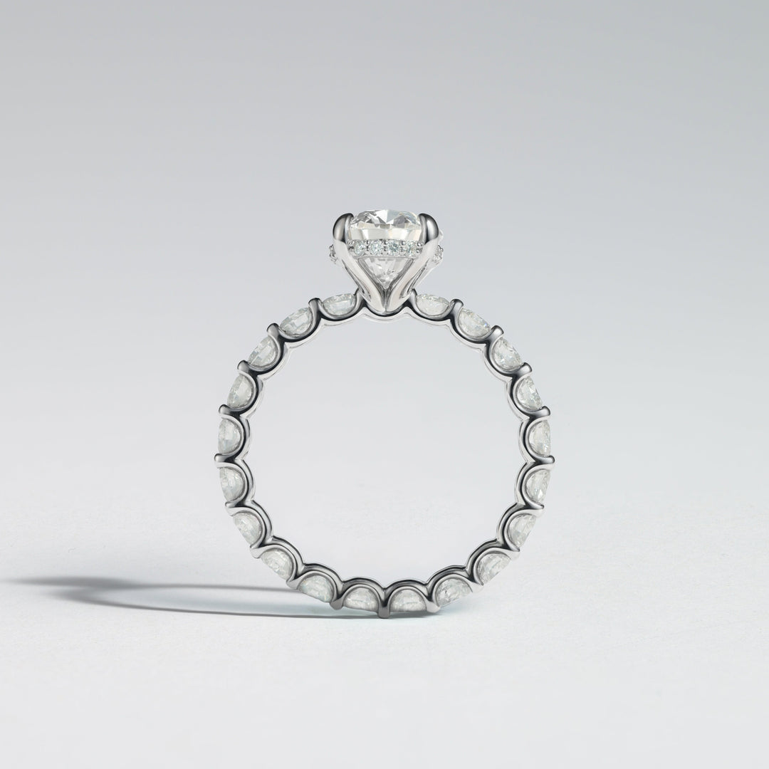 A silver-toned diamond ring featuring a heart-shaped diamond solitaire at the top and a continuous row of small round diamonds along the band, shown on a light gray background #material_white
