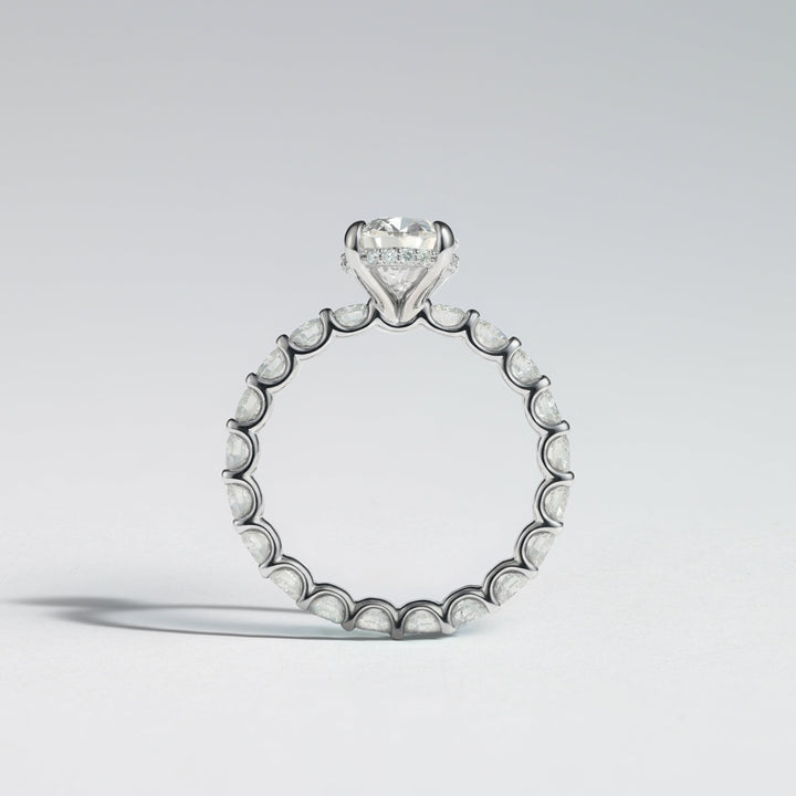 A silver-toned diamond ring featuring a heart-shaped diamond solitaire at the top and a continuous row of small round diamonds along the band, shown on a light gray background #material_white