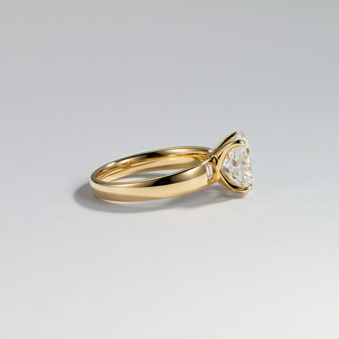 A yellow gold ring with a triangular clear gemstone in a prong setting, shown on a clean light gray background #material_gold