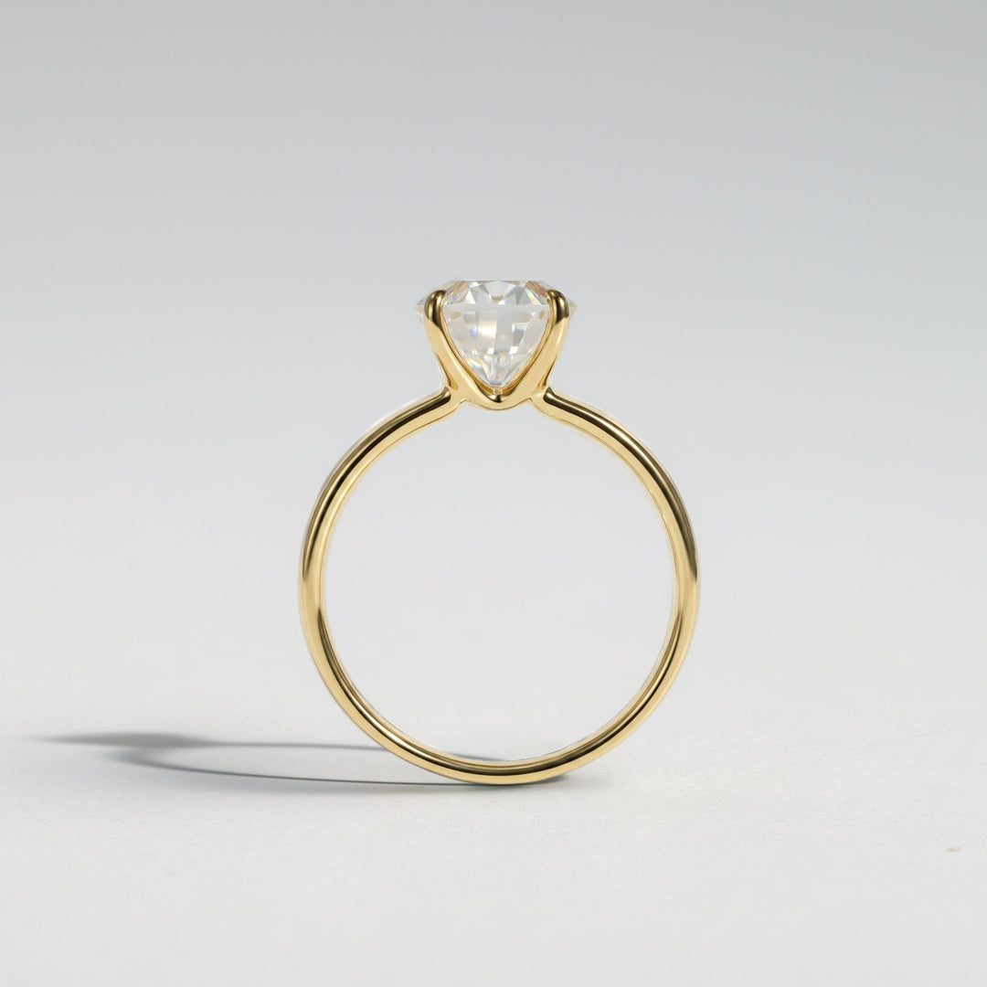 A yellow gold solitaire ring featuring a heart-shaped clear gemstone in a prong setting, photographed on a clean light gray background #material_gold