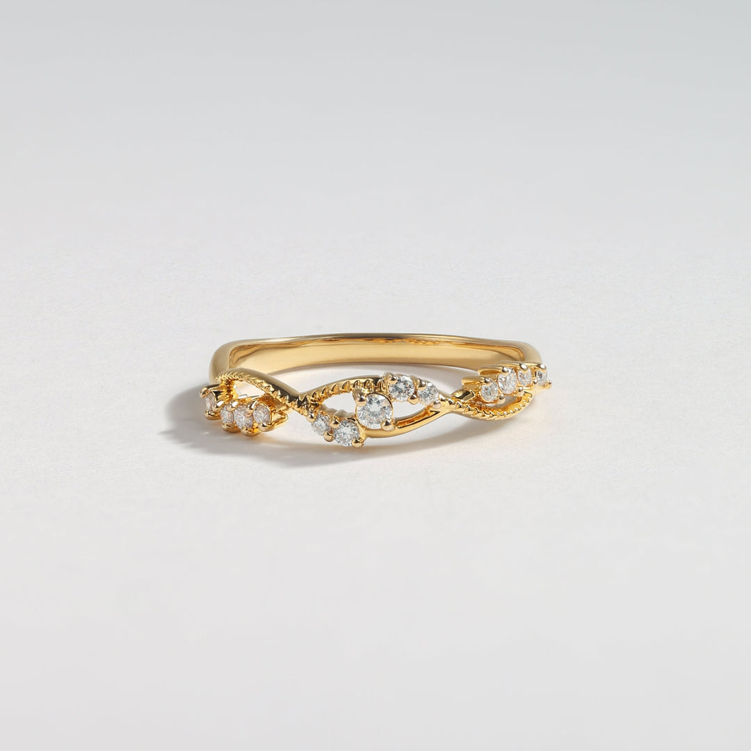 A gold ring featuring a twisted vine design adorned with small clear gemstones, photographed on a clean, light gray background #material_gold