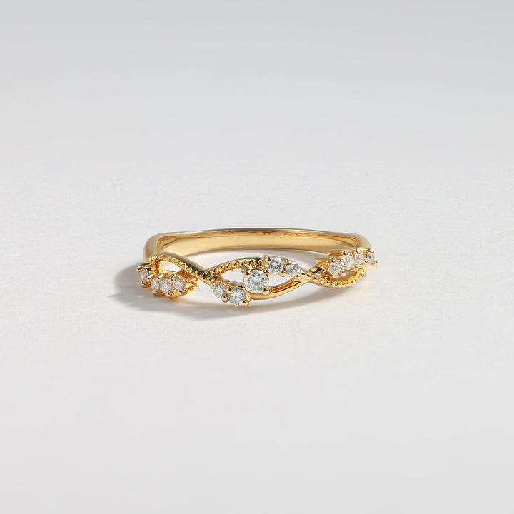 A gold ring featuring a twisted vine design adorned with small clear gemstones, photographed on a clean, light gray background #material_gold