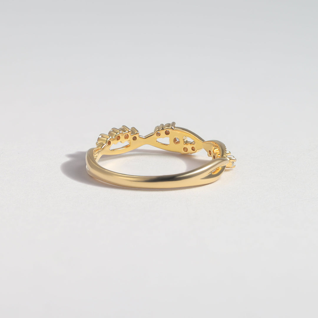 A gold ring with a curved, openwork design featuring small clear gemstones, photographed on a clean light gray background #material_gold