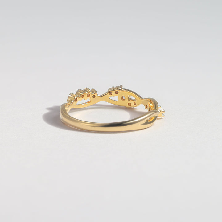 A gold ring with a curved, openwork design featuring small clear gemstones, photographed on a clean light gray background #material_gold