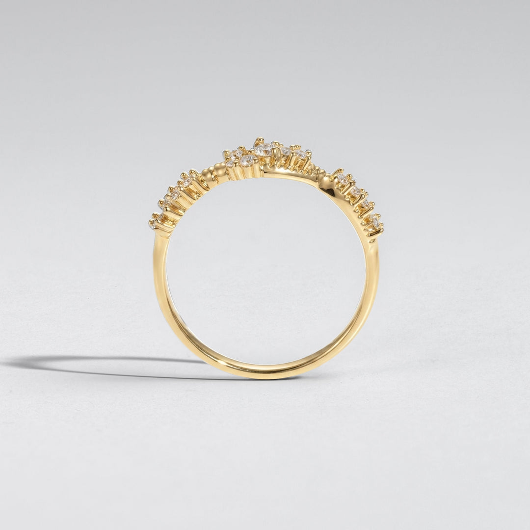 A gold ring with a delicate, openwork floral or crown-like top setting, photographed on a clean light gray background #material_gold