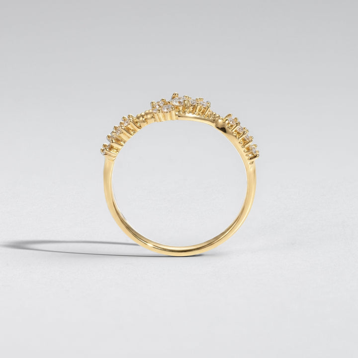 A gold ring with a delicate, openwork floral or crown-like top setting, photographed on a clean light gray background #material_gold