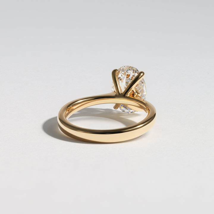 A yellow gold solitaire engagement ring with a round brilliant-cut diamond, shown on a clean light gray background #material_gold