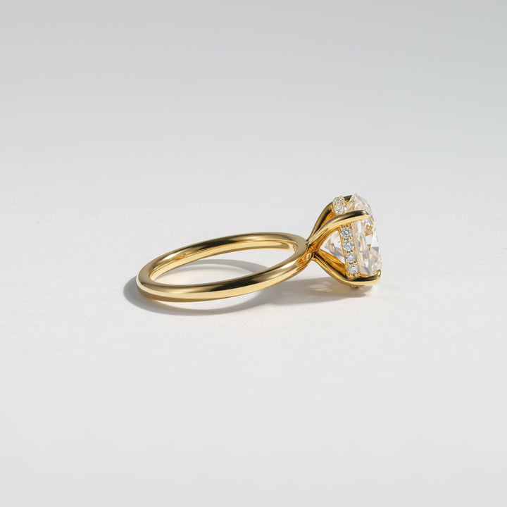A gold ring with a triangular clear gemstone in a prong setting, shown on a clean light gray background #material_gold