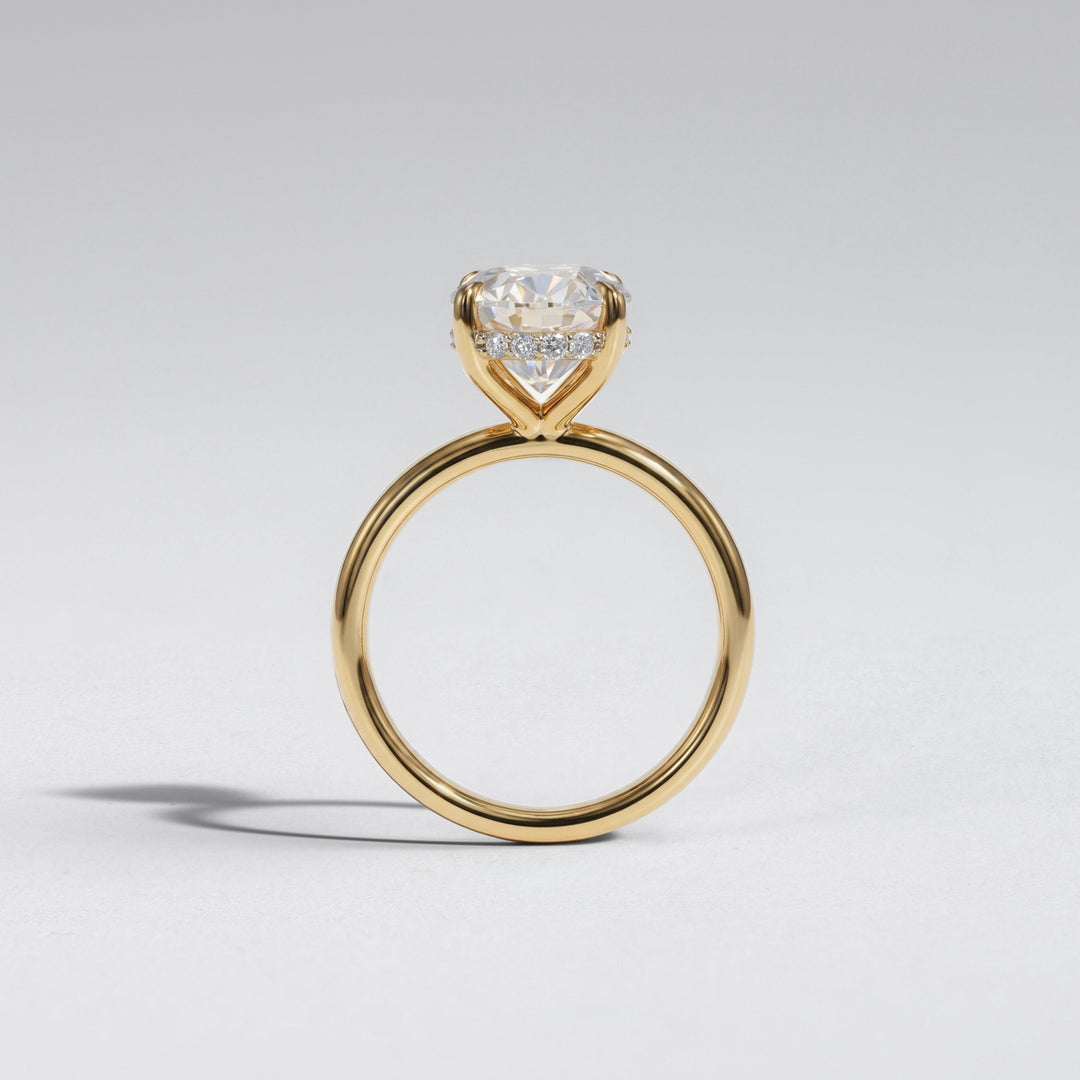 A yellow gold ring with a heart-shaped diamond solitaire setting, shown on a neutral light gray background #material_gold