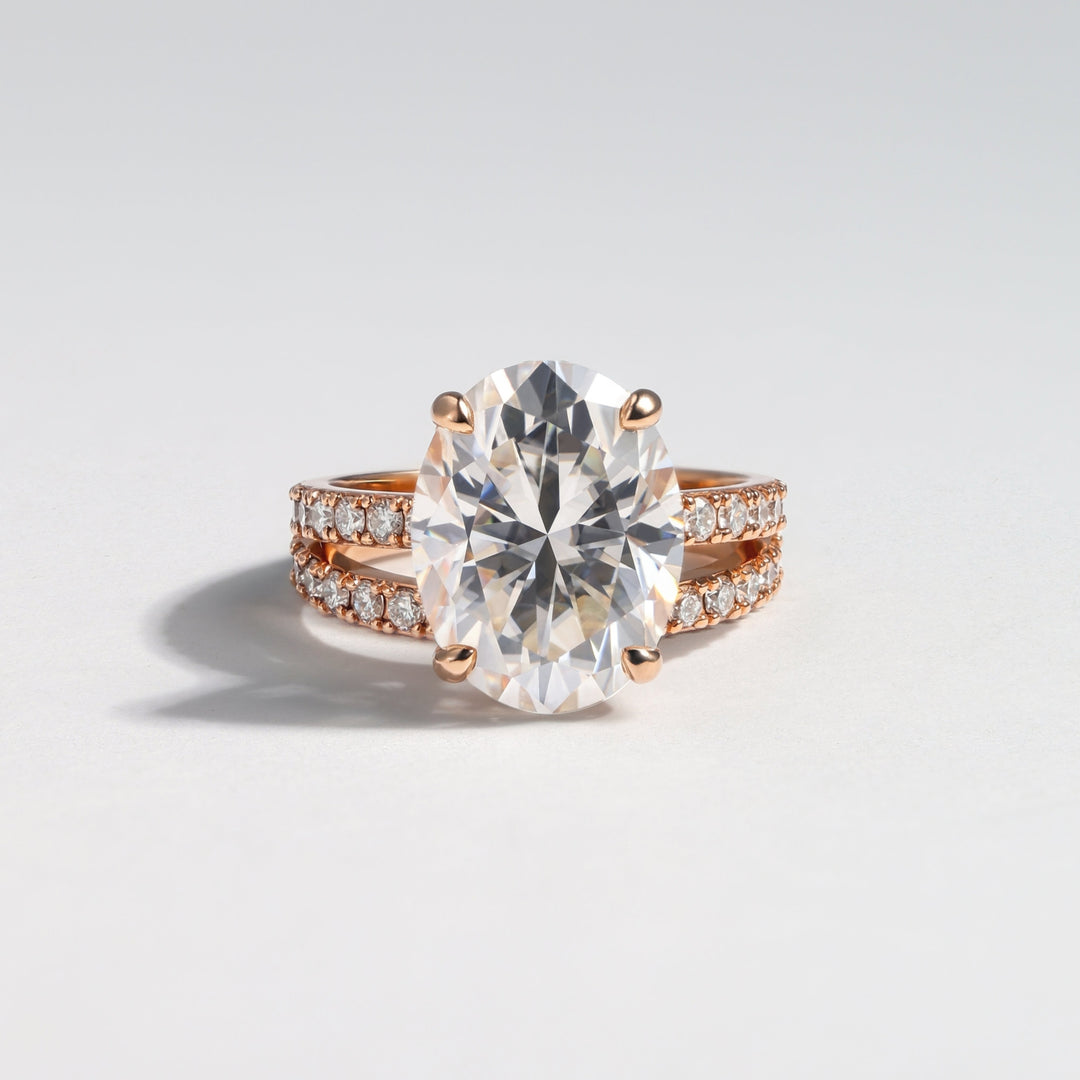 An oval-cut diamond engagement ring with a rose gold band accented by small pavé diamonds, photographed on a clean light gray background #material_rose