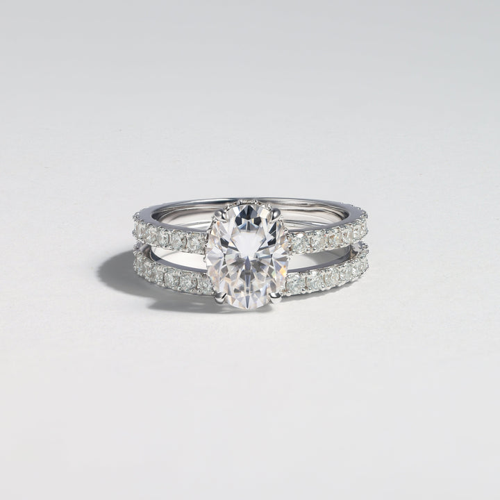 A double-band silver ring featuring a central oval-cut clear gemstone and pavé-set smaller stones along the bands, photographed on a light gray background #material_white
