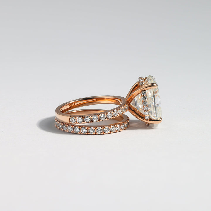 A rose gold engagement ring with a large oval-cut center stone and a matching pavé band, photographed on a clean light gray background #material_rose