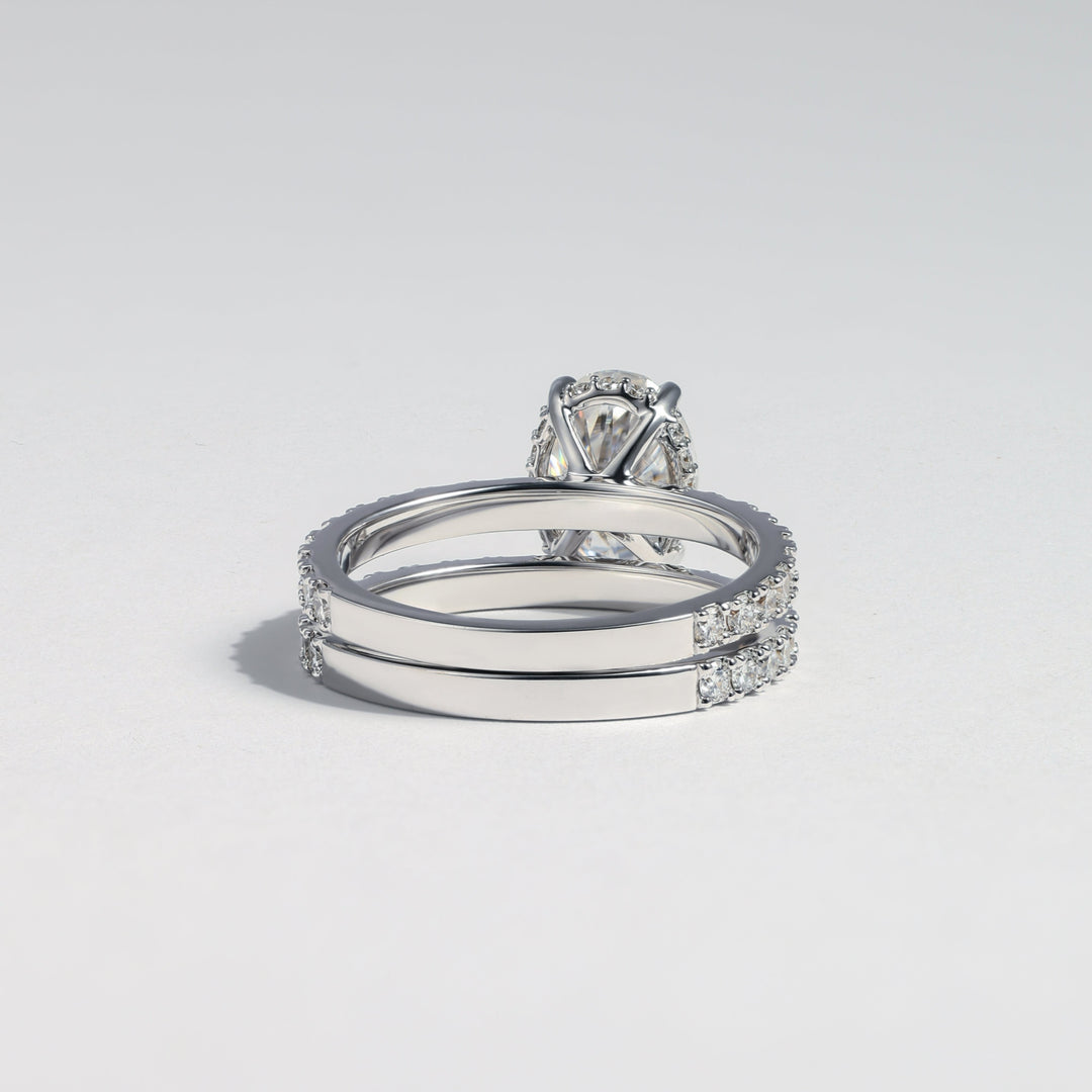 A silver-toned ring set featuring a solitaire diamond engagement ring paired with two matching band rings, all set with small pavé diamonds, photographed on a light gray background #material_white