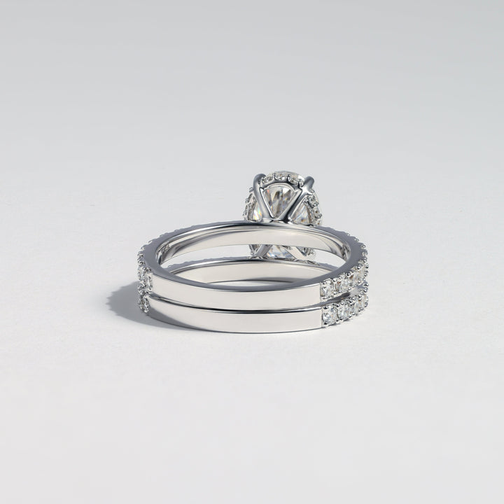 A silver-toned ring set featuring a solitaire diamond engagement ring paired with two matching band rings, all set with small pavé diamonds, photographed on a light gray background #material_white