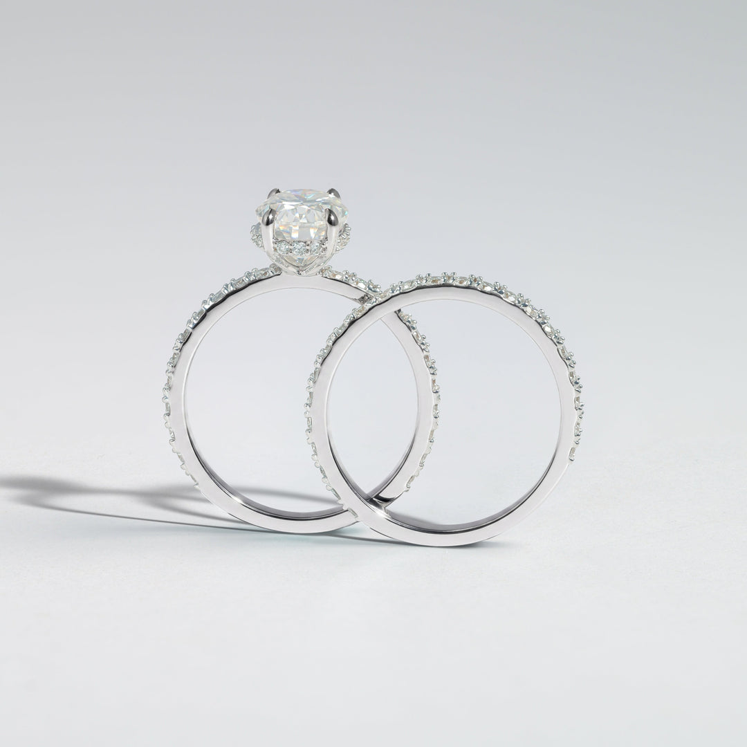 A silver engagement ring with a round-cut diamond solitaire and a matching diamond band ring, displayed on a clean light gray background #material_white