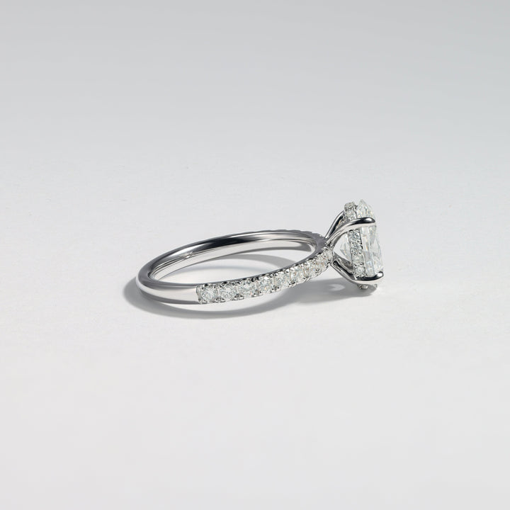 A silver-toned diamond ring with a marquise-cut center stone and pavé-set diamonds along the band, photographed on a clean light gray background #material_white