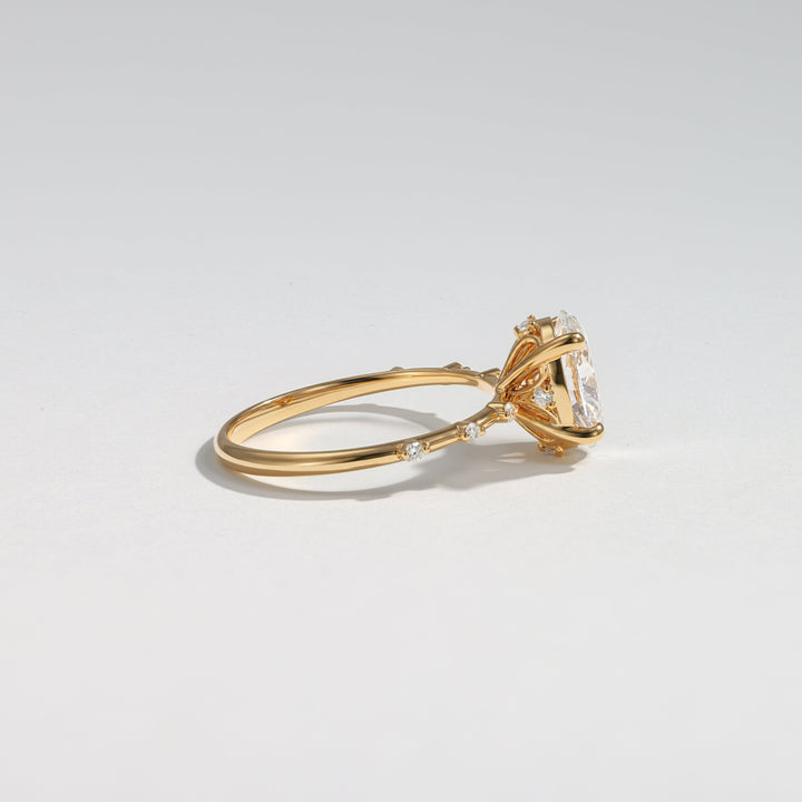 A gold ring with a large clear rectangular gemstone and small side stones, photographed on a clean light gray background #material_gold
