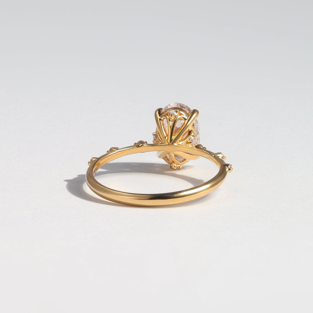 A gold ring with a decorative fan-like top and a clear central gemstone, photographed on a clean light gray background #material_gold