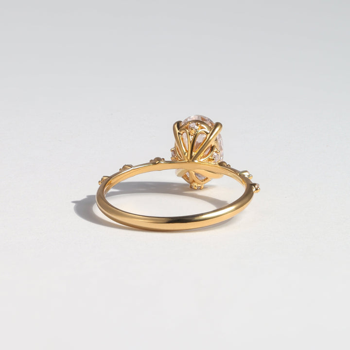 A gold ring with a decorative fan-like top and a clear central gemstone, photographed on a clean light gray background #material_gold