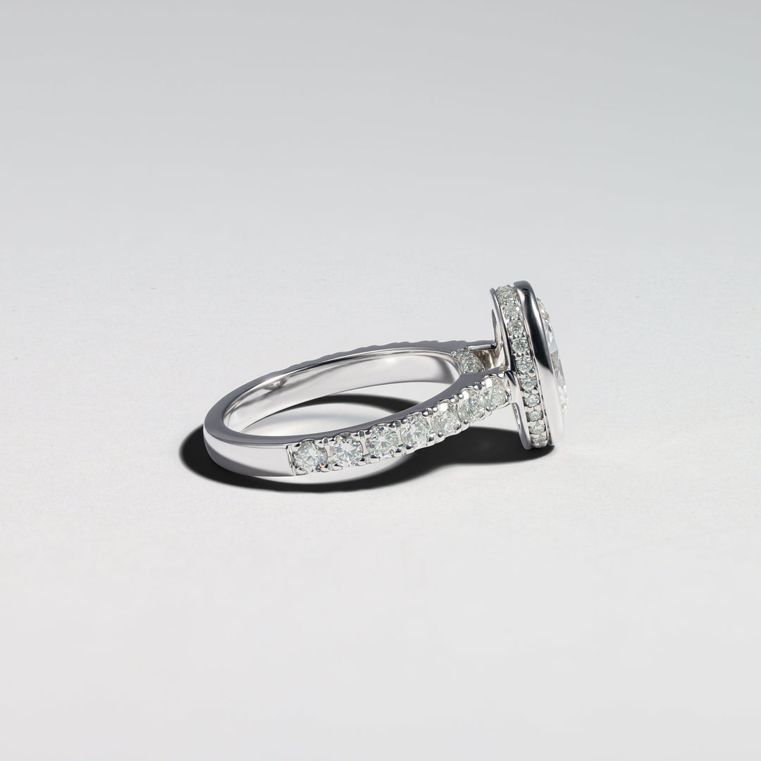 A silver-toned diamond ring with a pavé band and a central round-cut gemstone, photographed on a clean light gray background #material_white
