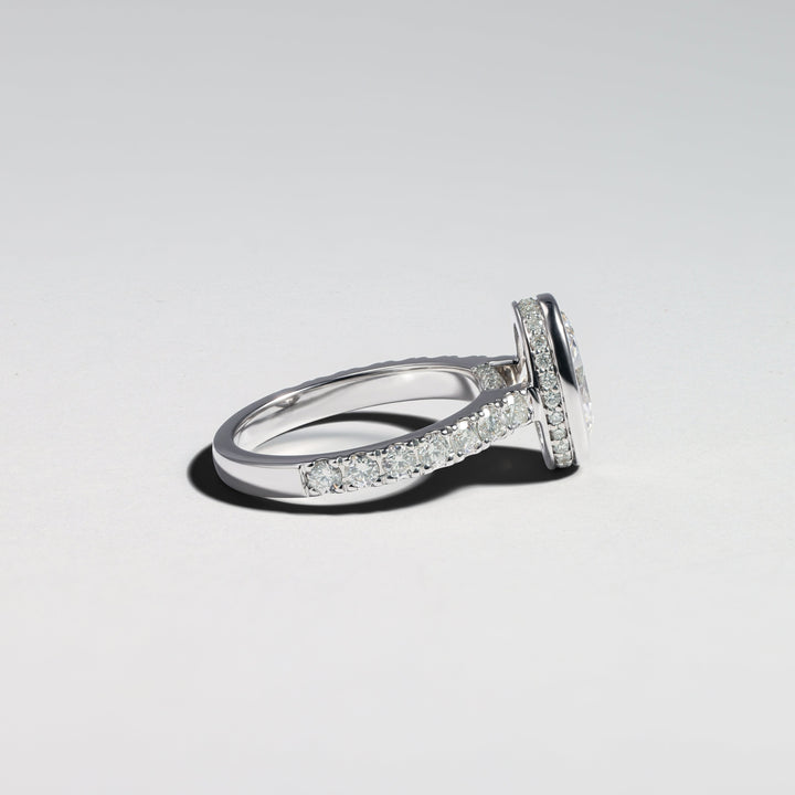 A silver-toned diamond ring with a pavé band and a central round-cut gemstone, photographed on a clean light gray background #material_white