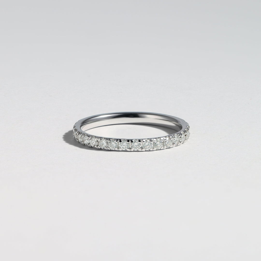 A thin silver band ring paved with small clear stones, photographed on a clean light gray background #material_white