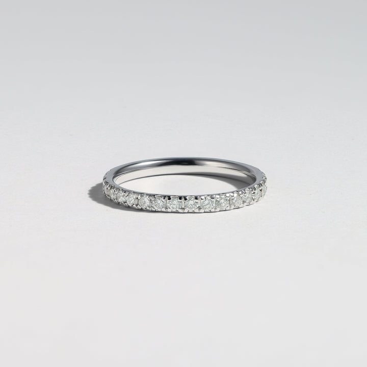 A thin silver band ring paved with small clear stones, photographed on a clean light gray background #material_white