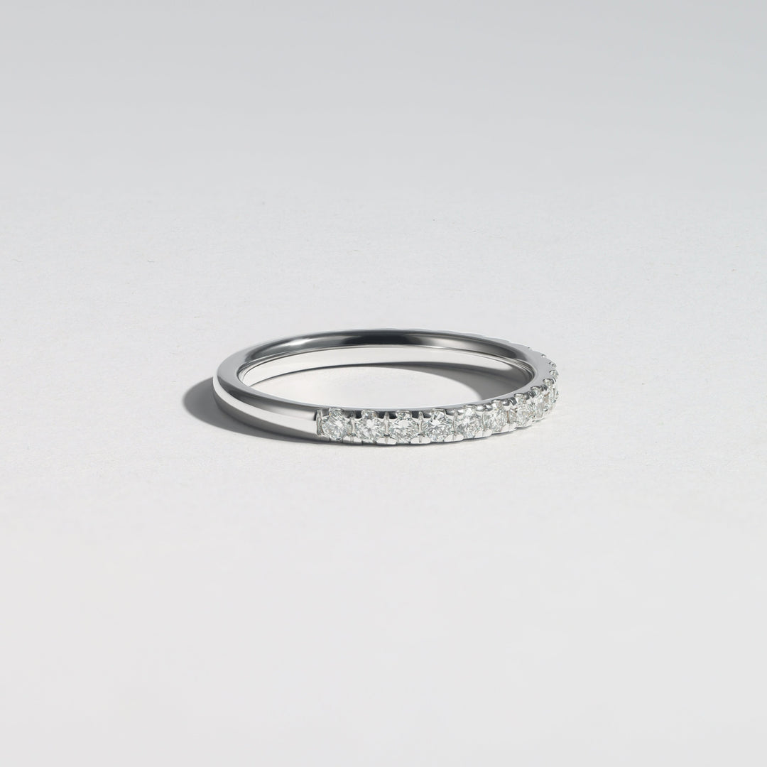A slim silver band ring featuring a pavé-set row of clear stones on one side, photographed on a clean light gray background #material_white
