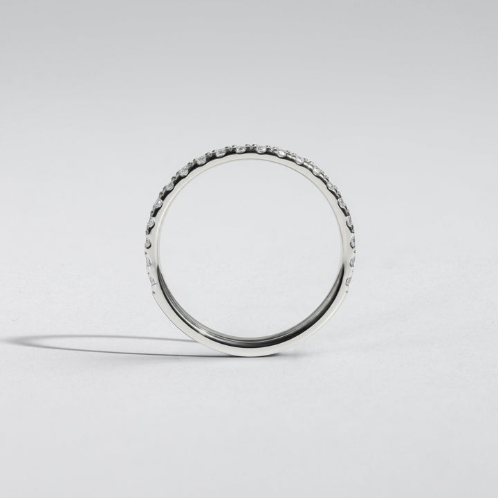 A silver band ring with a row of small clear stones around the outer edge, photographed on a clean light gray studio background #material_white
