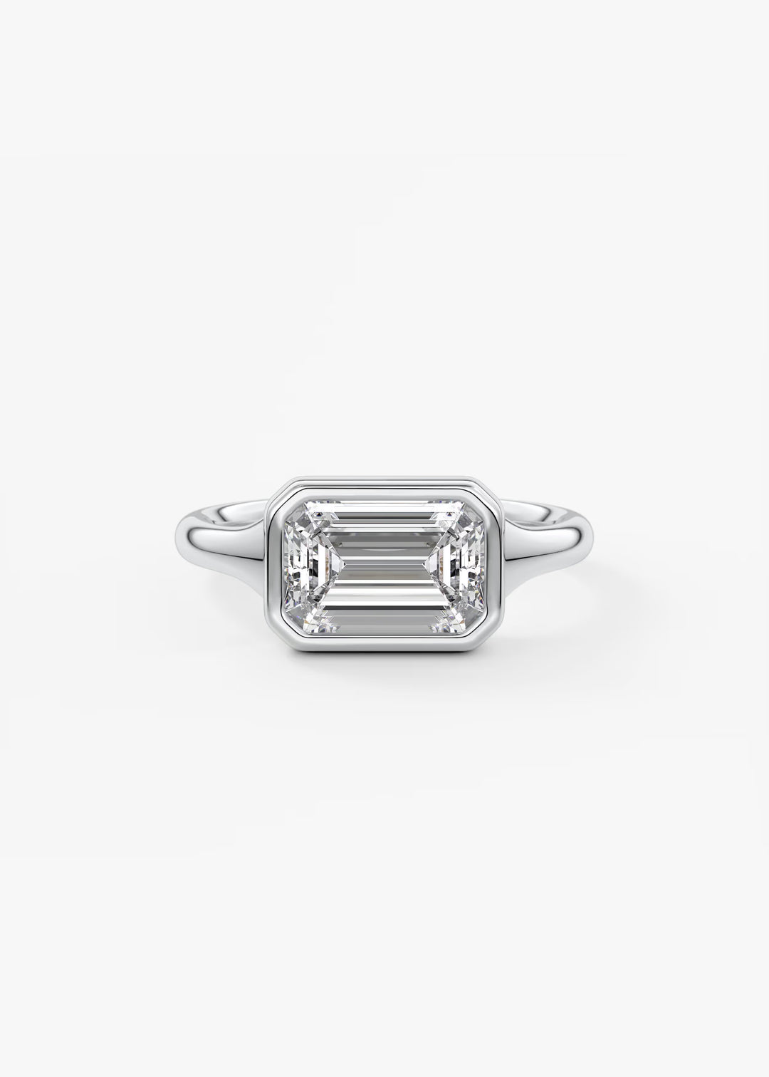 An emerald-cut diamond ring in a silver-toned metal setting, centered on a clean white background. #material_white