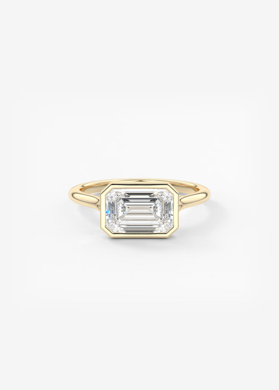 A yellow gold ring featuring a large, bezel-set emerald-cut clear gemstone, photographed against a seamless white background.#material_gold