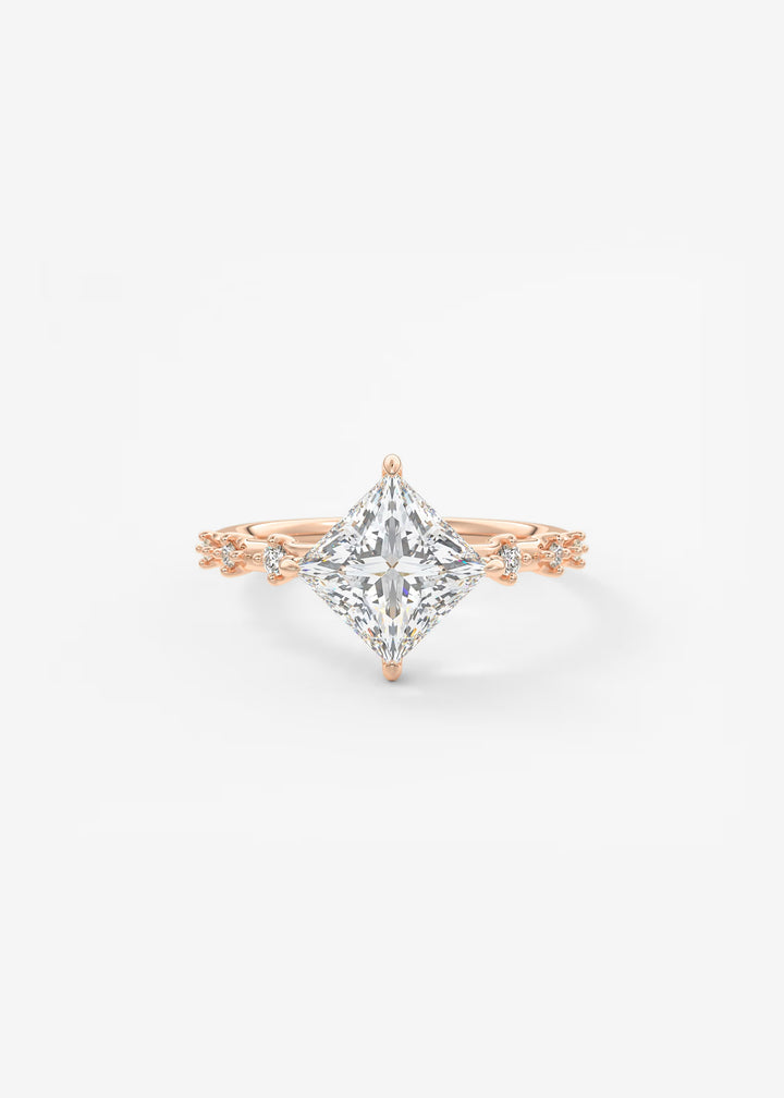 A rose gold ring featuring a large princess-cut diamond center stone and smaller diamonds along the shoulders, set against a clean white background.#material_rose