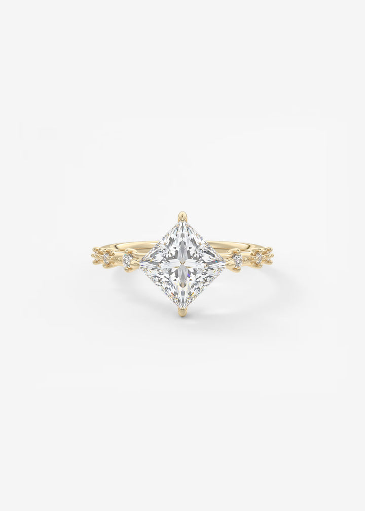 A yellow gold ring featuring a large princess-cut clear center stone with delicate gold side accents, set against a clean white background.#material_gold