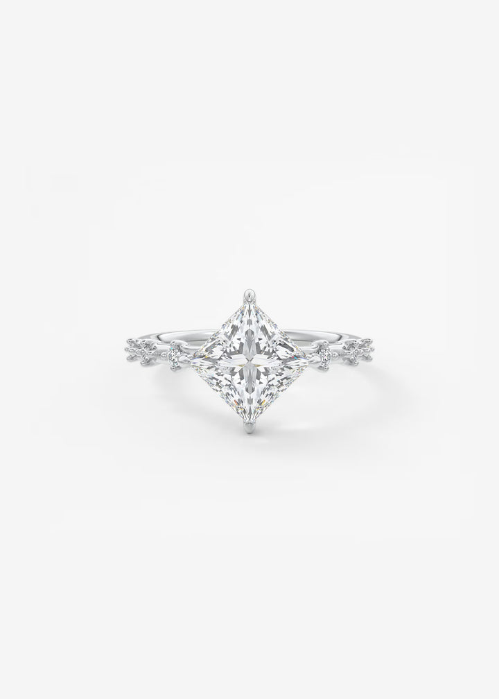 A silver-toned diamond engagement ring featuring a large princess-cut center stone and a delicate diamond-accented band, set against a clean white background.#material_white